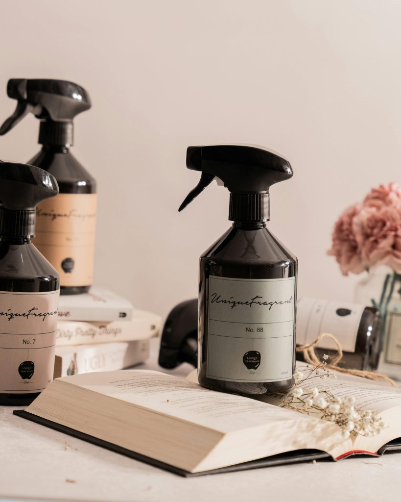 Stylish spray bottles of fragrance with pink flowers and books for a clean, modern aesthetic.